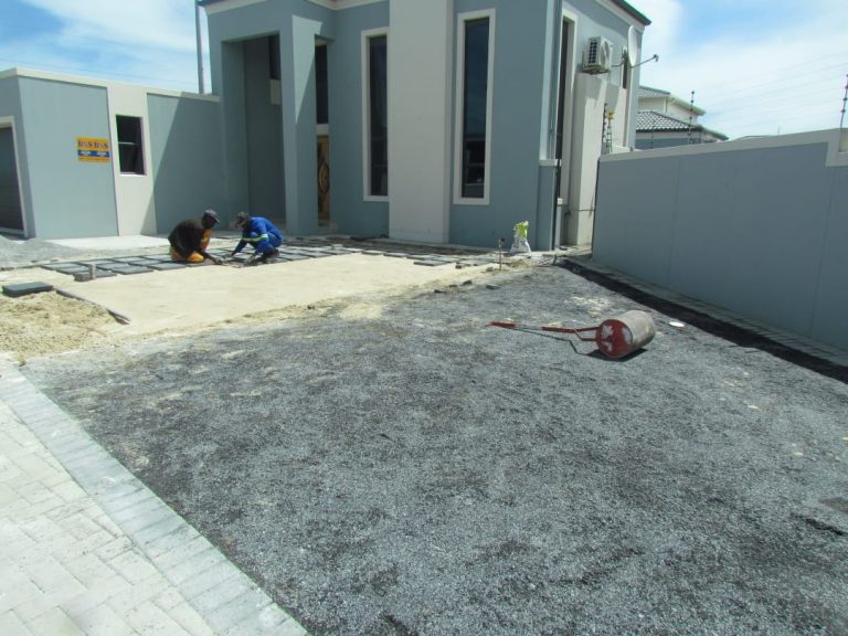 Artifical grass with square cut outs between paving BEFORE 